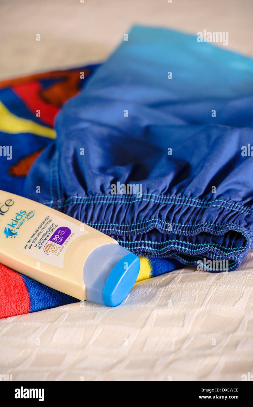 Swimming shorts, beach towel and a high factor sunscreen. Stock Photo