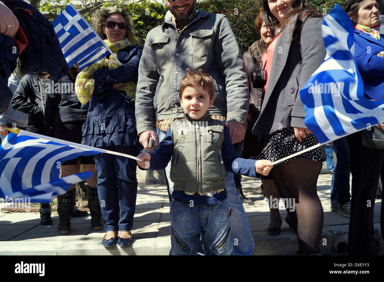 Thessaloniki, Greece. 25th March 2014. A child waving Greek flags during the annual parade on Tuesday, celebrating the Greek independence day, in the northern Greek port city of Thessaloniki. Greeks celebrated their national independence day amid tight security and protest in the northern port city of Thessaloniki, as school teachers staged a protest against planned layoffs as part of governments cost cutting reforms.  Credit:  Orhan Tsolak/Alamy Live News Stock Photo