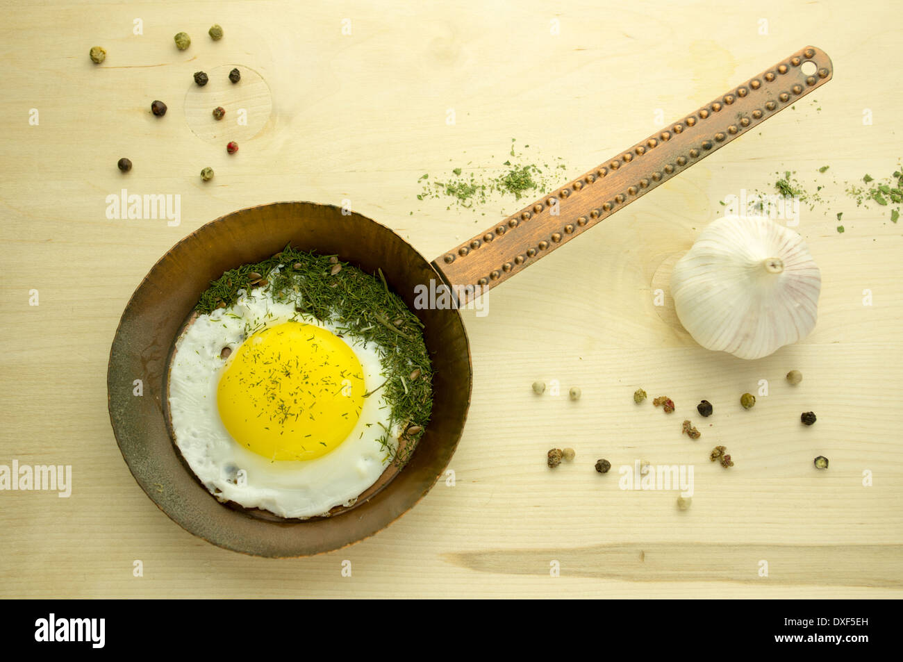 Fried egg in a copper pan on a wooden board Stock Photo