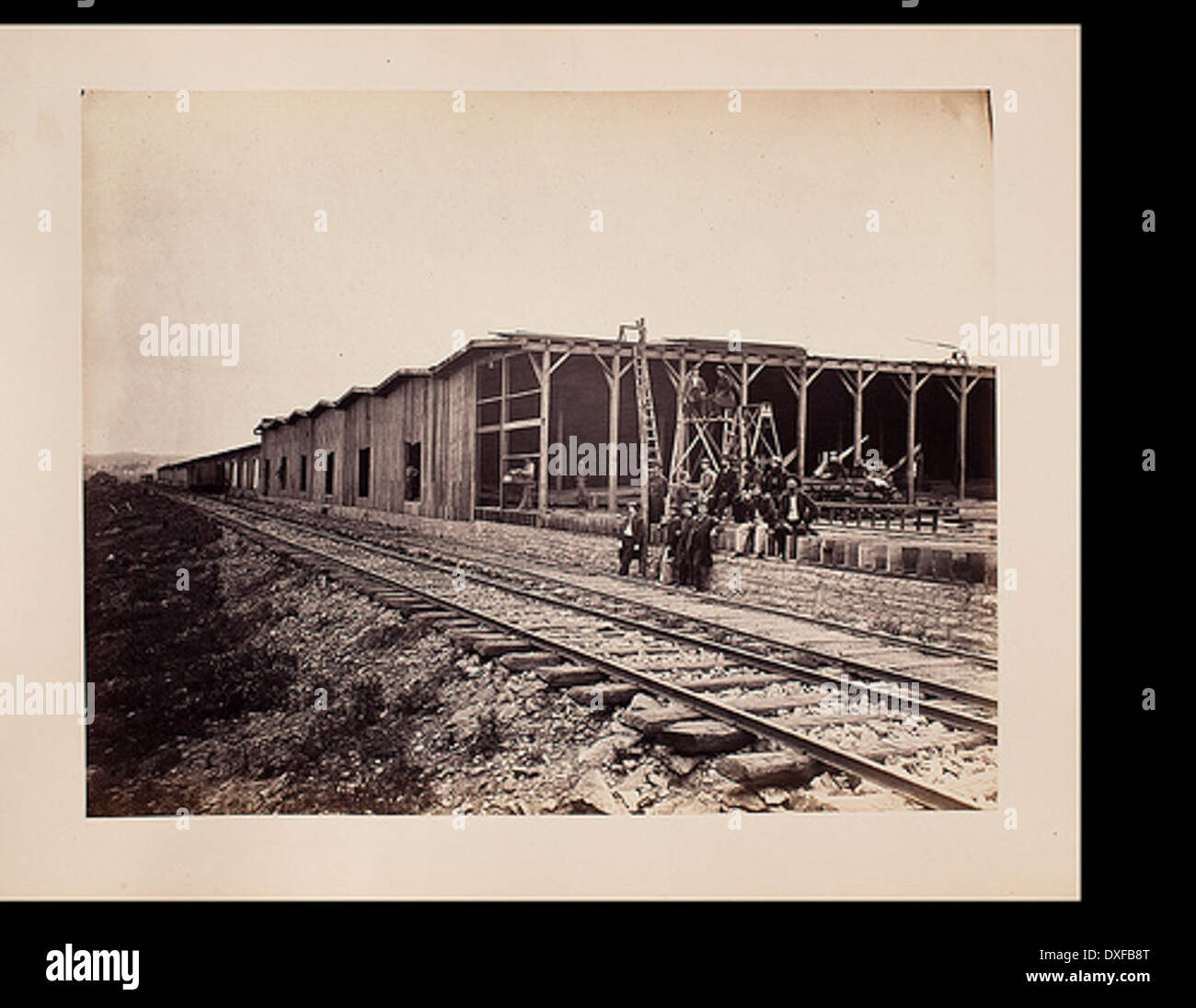 Men along railroad, in front of warehouses under construction Stock Photo