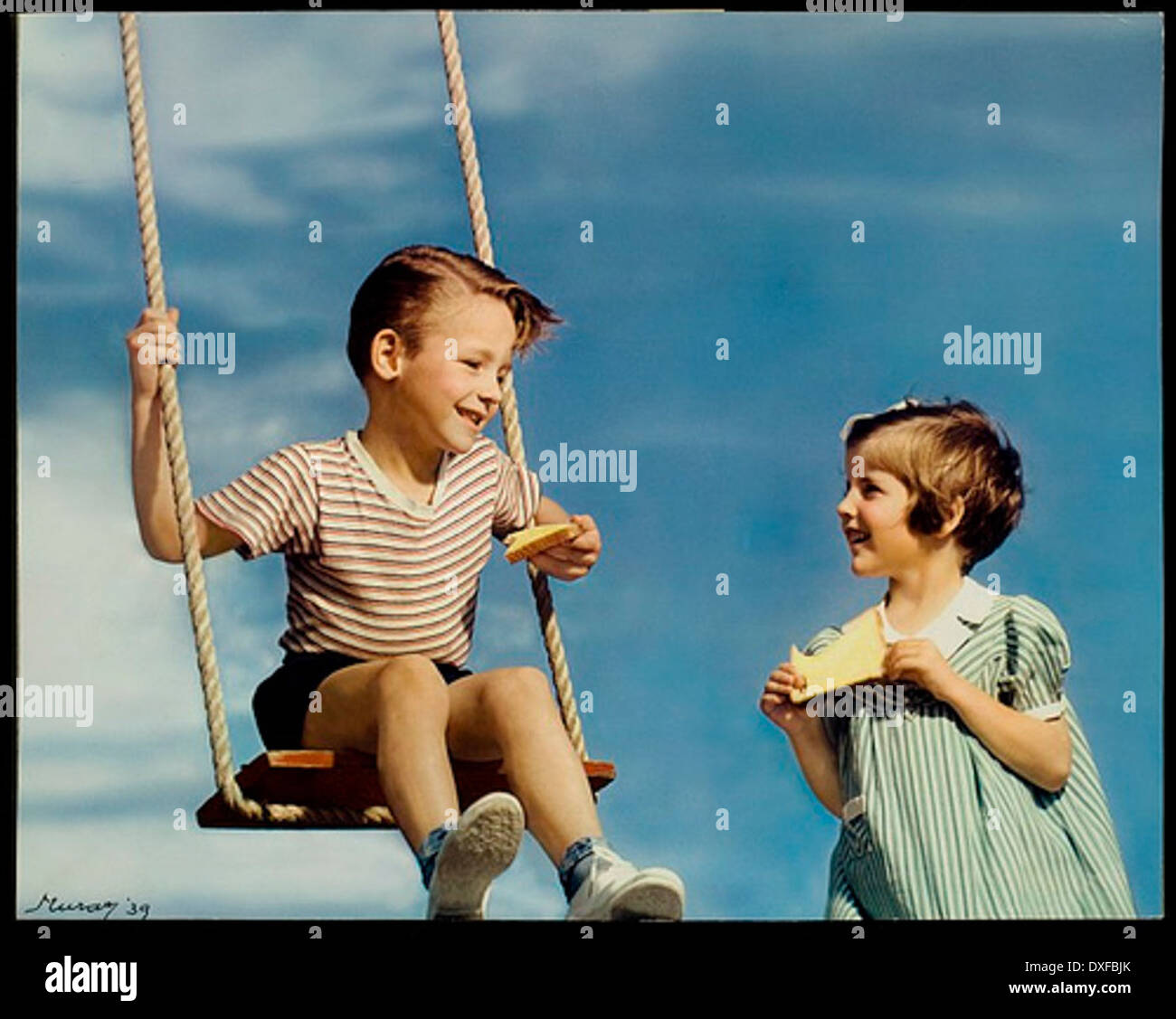 A vintage photograph depicting children playing on a swing, with NUCOA Margarine prominently featured in the image. This nostalgic scene reflects past times and captures the carefree nature of childhood in an era of simpler pleasures, with the margarine brand adding a touch of historical advertising. Stock Photo