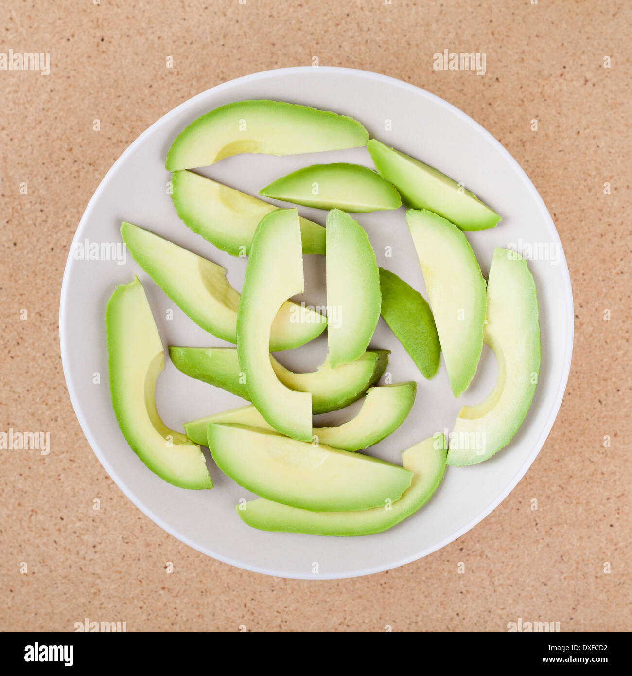 Fresh sliced avocado on plate, over wooden background. Stock Photo