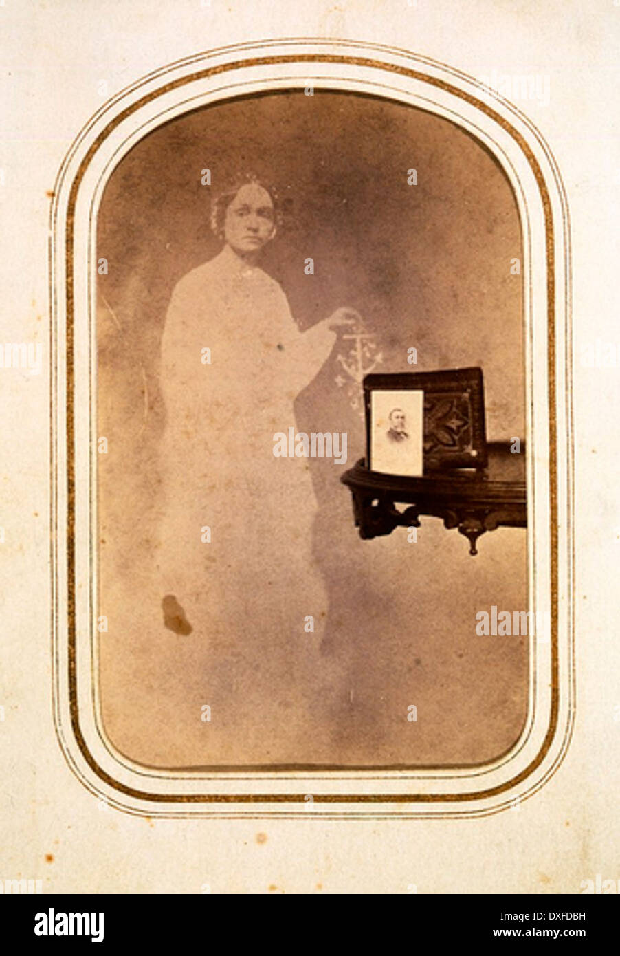 Spirit Photograph [Woman's spirit behind table with photograph] Stock Photo