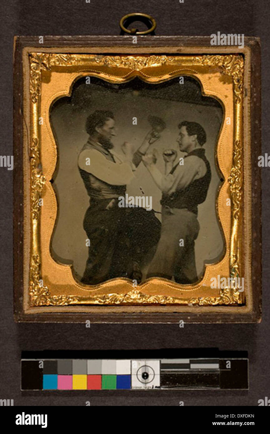 This image depicts two men engaged in a boxing match. The photo captures the intensity of the fight, a common subject of historical sports photography. Stock Photo