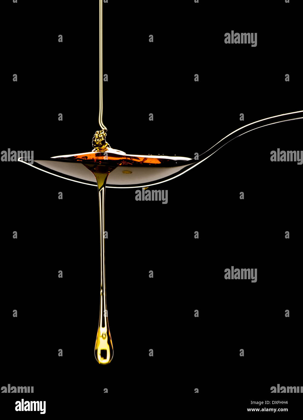 Golden syrup treacle pouring on to metal spoon and dripping off