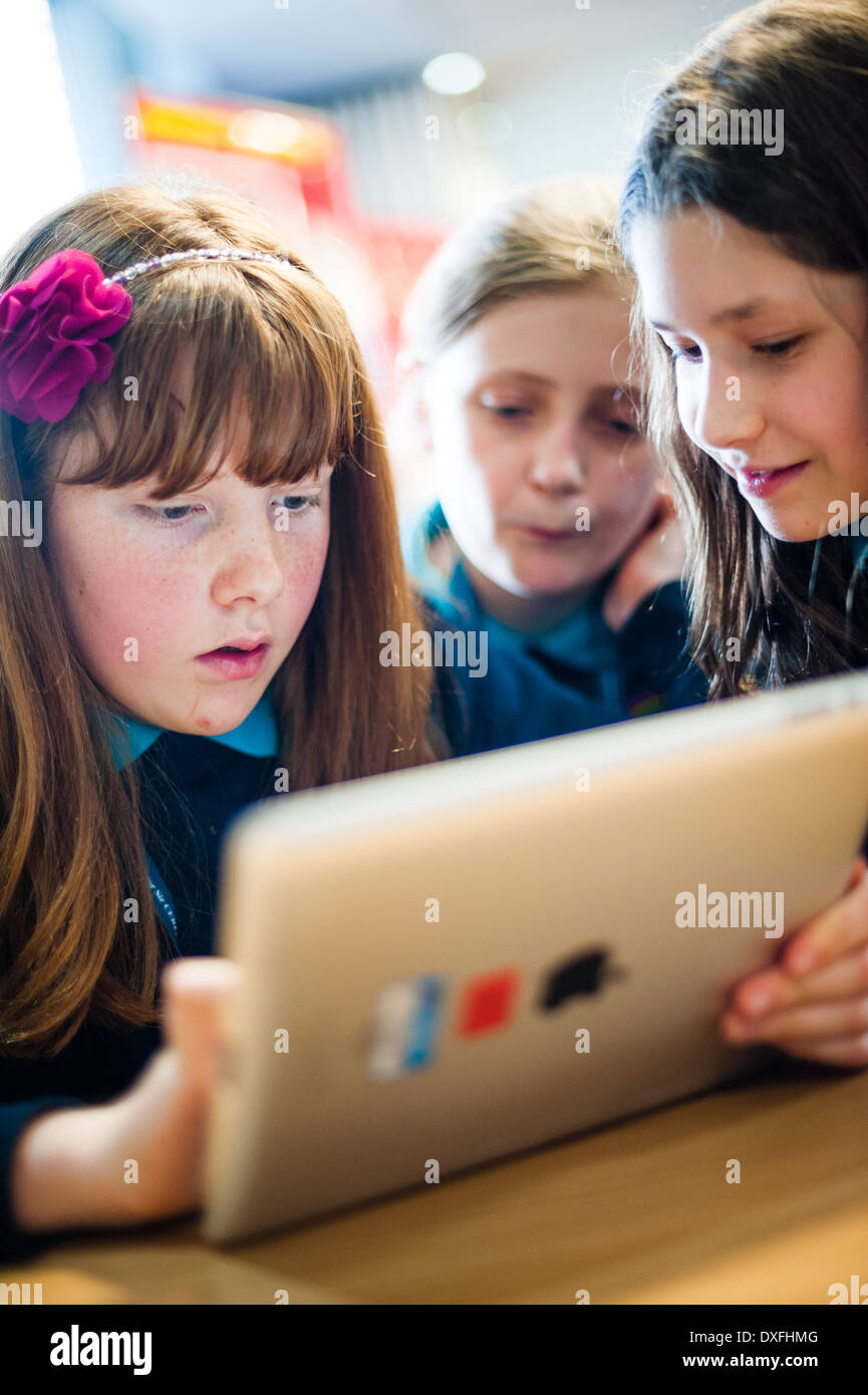 Primary school girls children using apple iPad tablet computers in