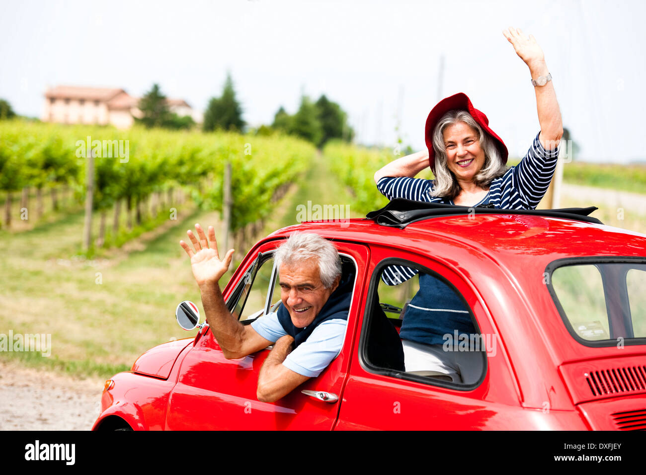 Mature couple enjoying a road trip in a small red car Stock Photo