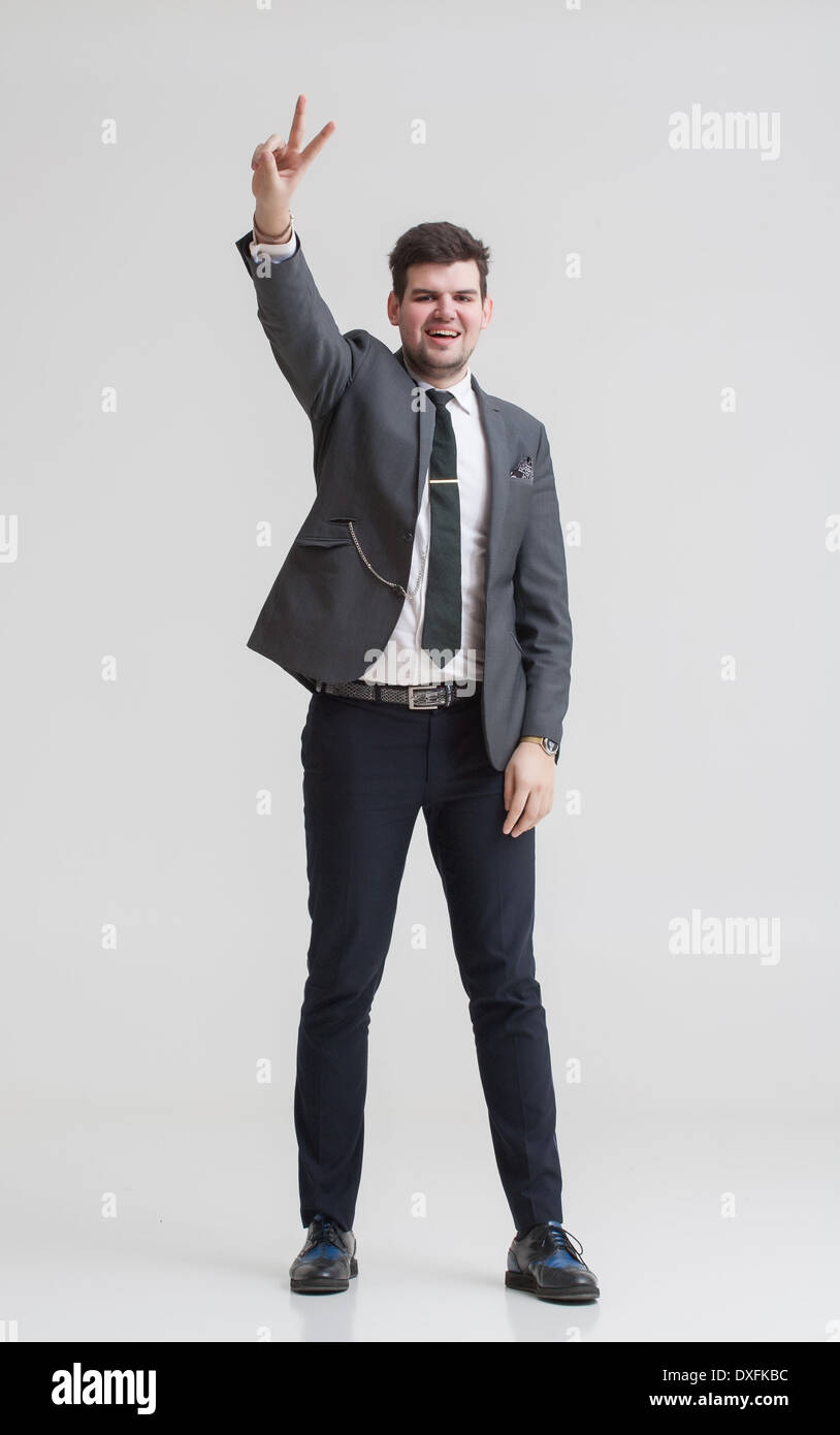Handsome Businessman in a nice suit showing signs by his hands. Tall man in a gray suit. Stock Photo