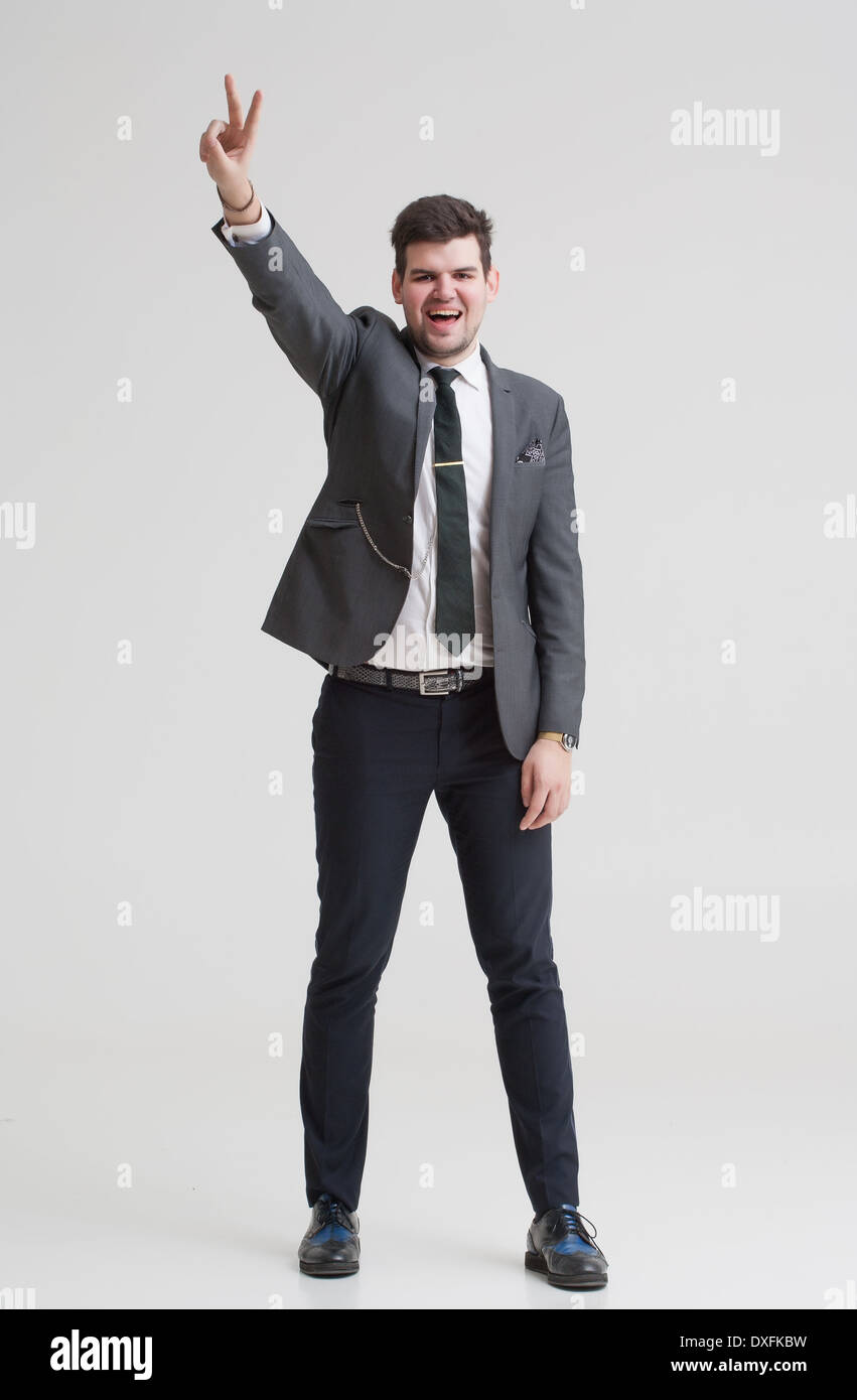 Handsome Businessman in a nice suit showing signs by his hands. Tall man in a gray suit. Stock Photo