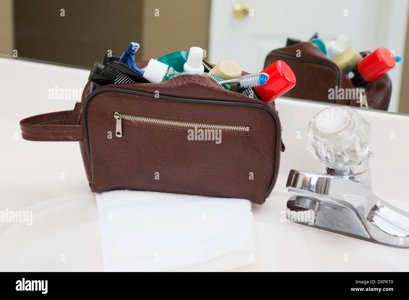 Men's toiletry travel bag on bathroom counter, filled with toothbrush, shaving cream, razor and other grooming products, USA Stock Photo