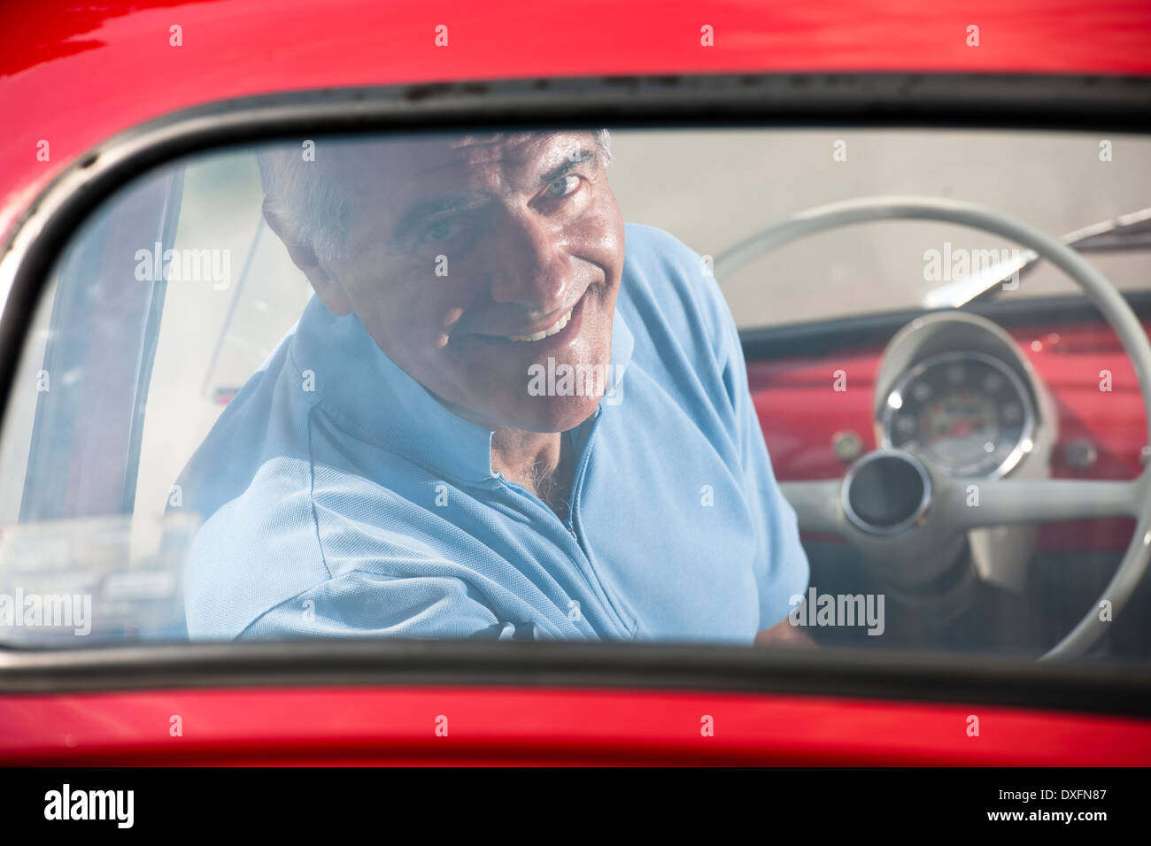 Mature man enjoying a road trip in a small red car Stock Photo