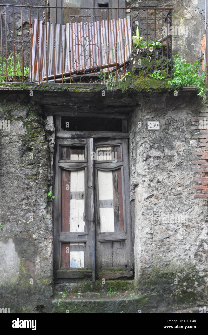 Old door and balcony of an abandoned dwelling in Southern Italian village of Delianuova Calabria Stock Photo
