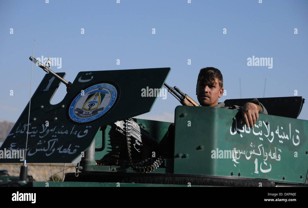 Kabul, Afghanistan. 25th Mar, 2014. An Afghan policeman keeps watch on a military vehicle at the site of an attack in Kabul, Afghanistan, March 25, 2014. A group of armed militants raided a sub-office of Afghan election commission in Darul Aman area in western Kabul Tuesday morning, leaving 10 people including five attackers dead. © Ahmad Massoud/Xinhua/Alamy Live News Stock Photo