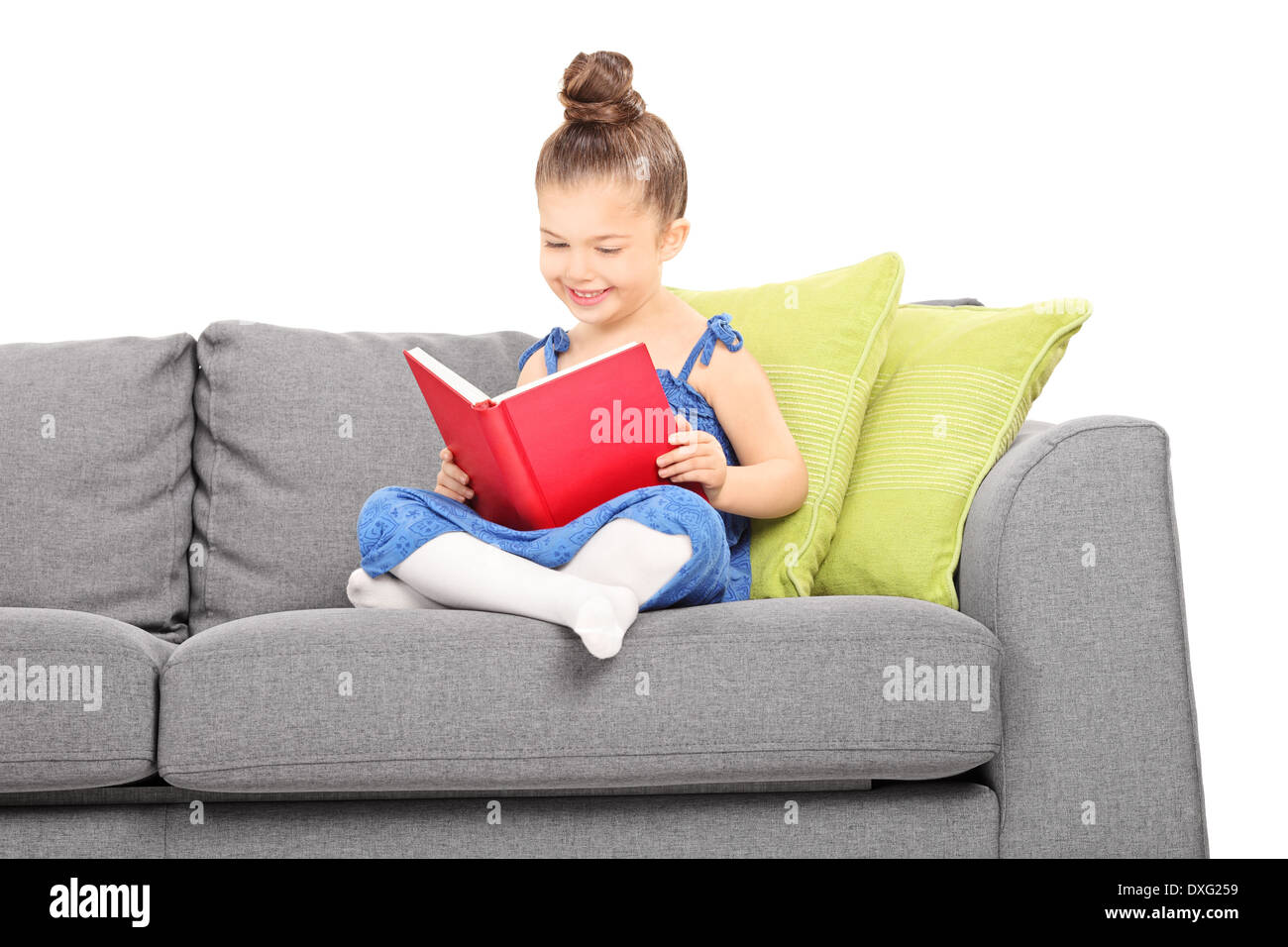 Little girl reading a book seated on sofa Stock Photo Alamy