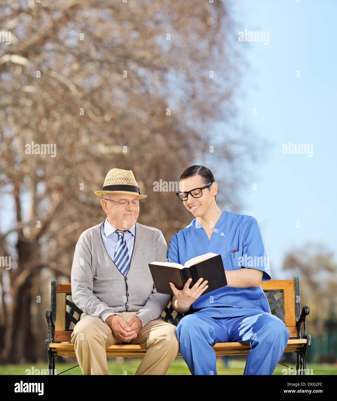 Male nurse reading to a senior in park Stock Photo