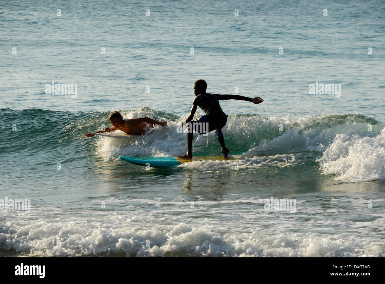 Young black Mozambican boy surfing with white boy at Tofo, Mozambique Stock Photo