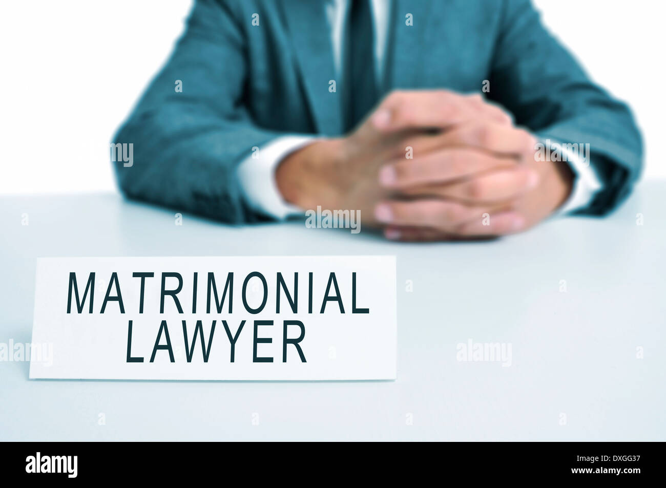 a man wearing a suit sitting in a desk with a desktop nameplate in front of him with the text matrimonial lawyer Stock Photo
