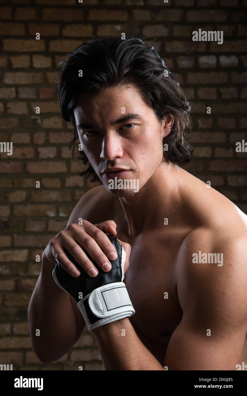 Bare chested young Malaysian boxer wearing fingerless boxing gloves