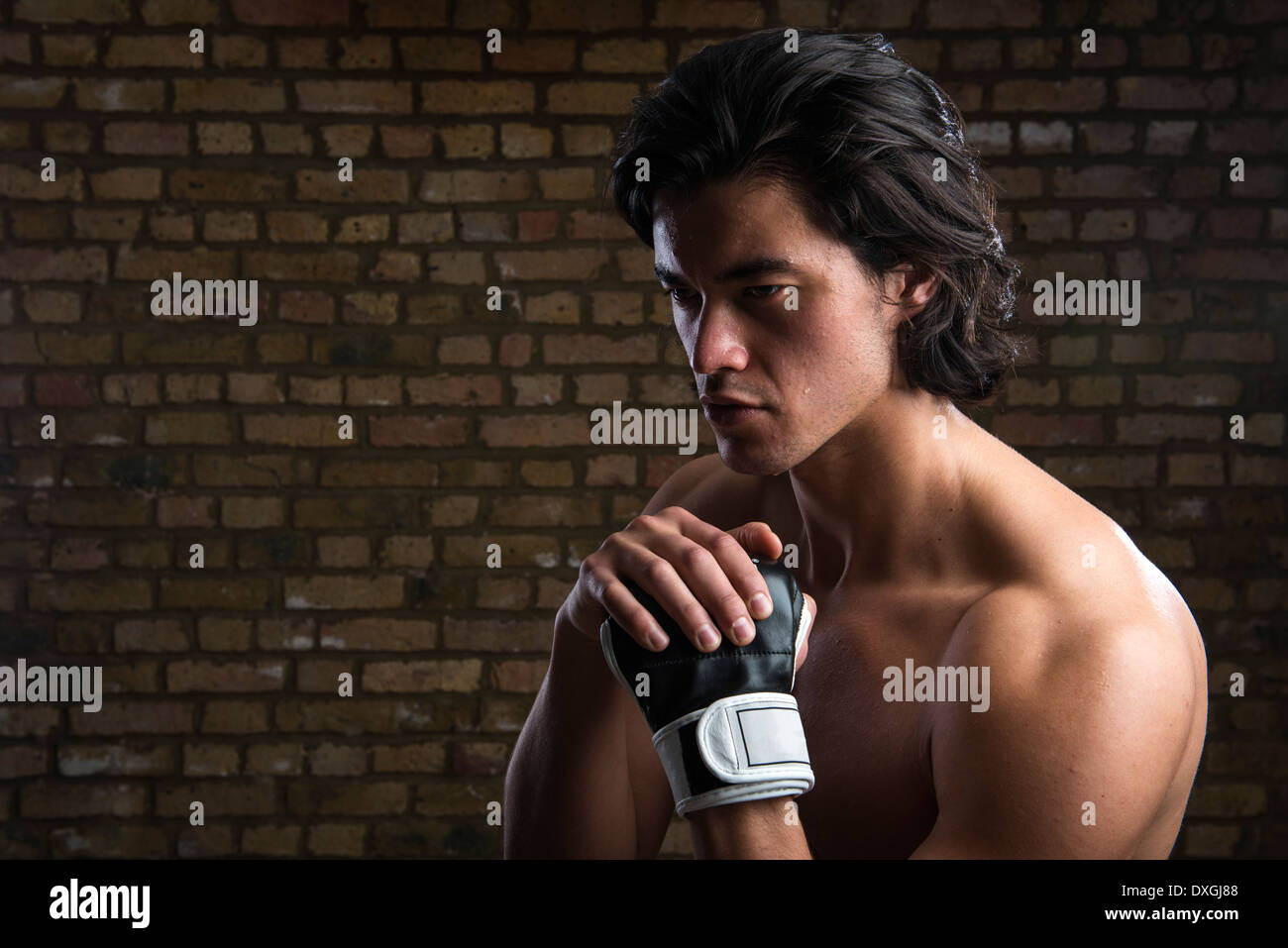 Bare chested young Malaysian boxer wearing fingerless boxing gloves