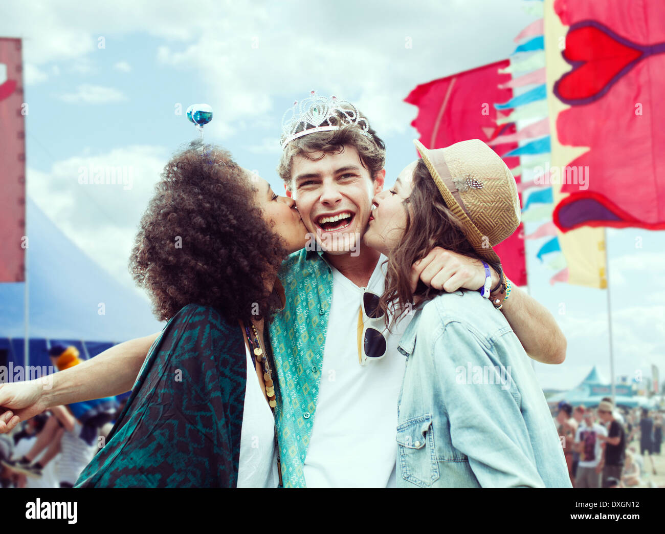 Women kissing manÍs cheek at music festival Stock Photo