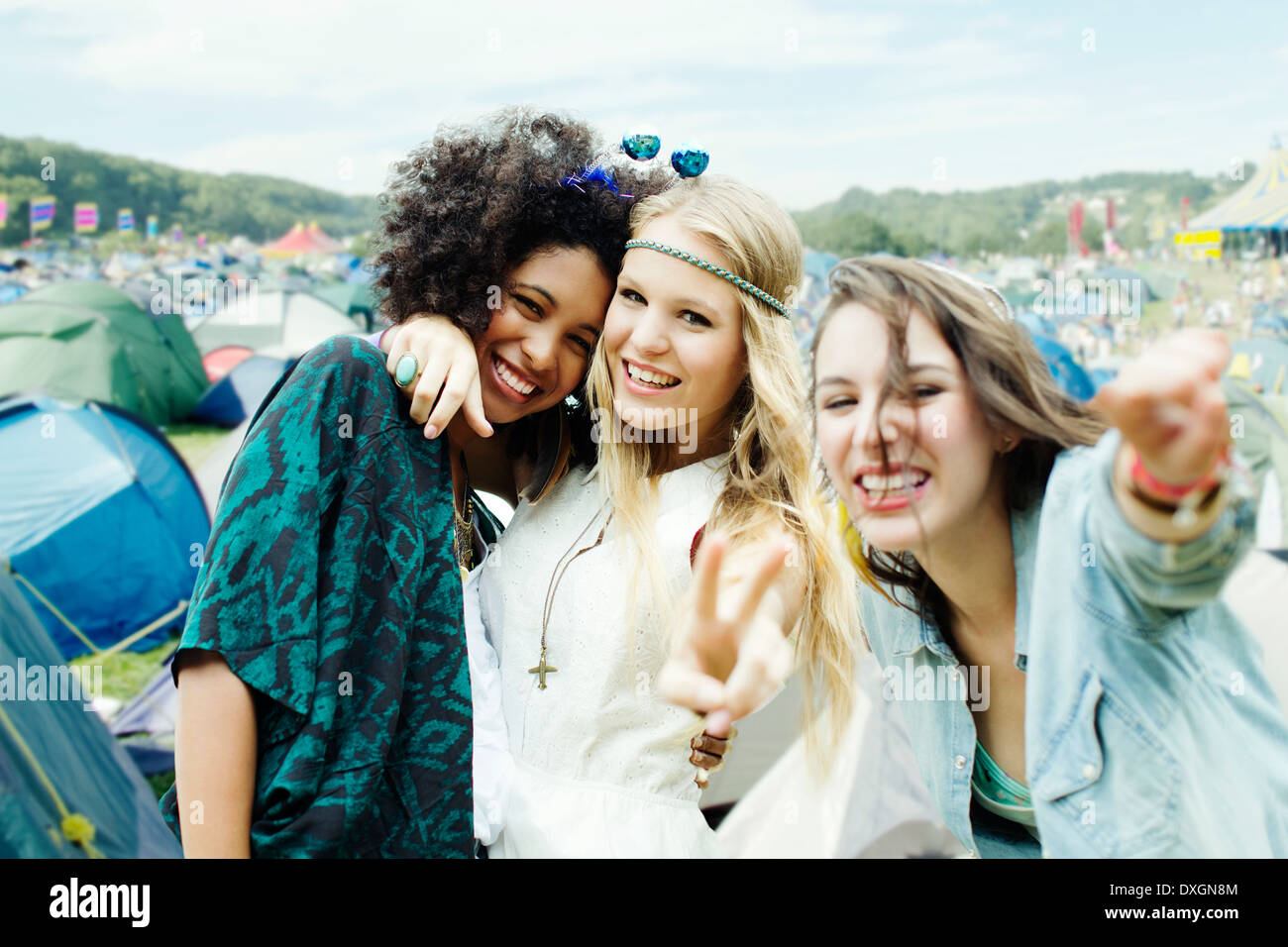 Friends hugging outside tents at music festival Stock Photo