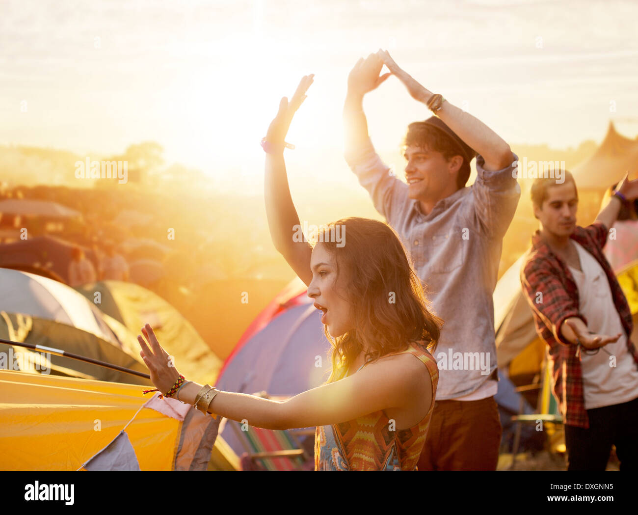 Friends dancing outside tents at music festival Stock Photo
