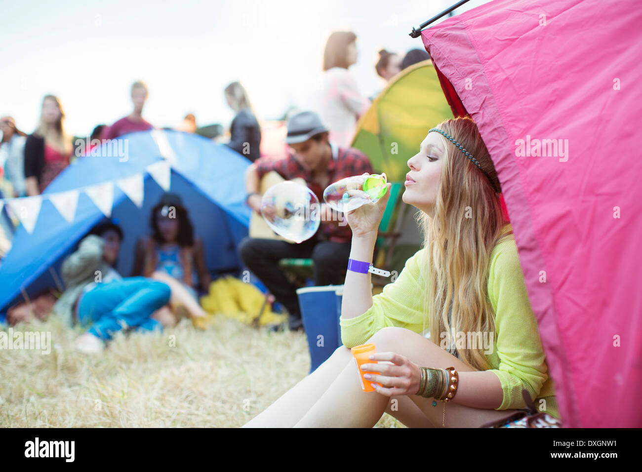 Woman blowing bubbles from tent at music festival Stock Photo