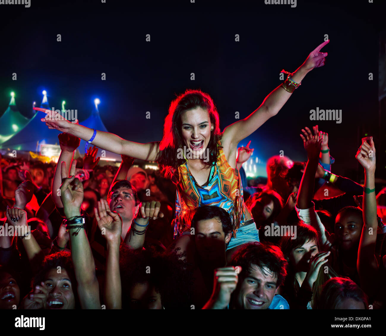 Cheering woman on manÍs shoulders at music festival Stock Photo