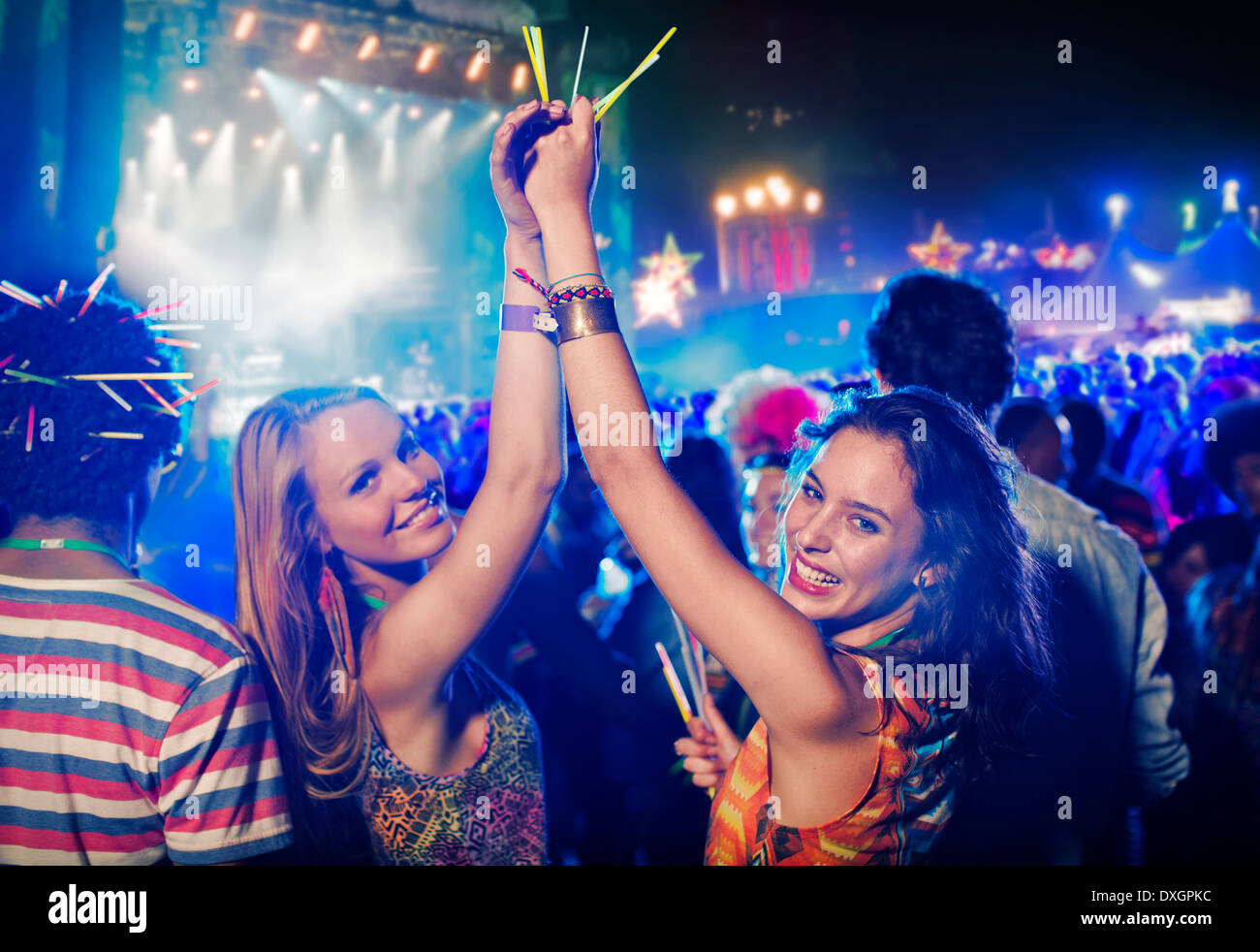 Portrait of cheering women with glow sticks at music festival Stock Photo