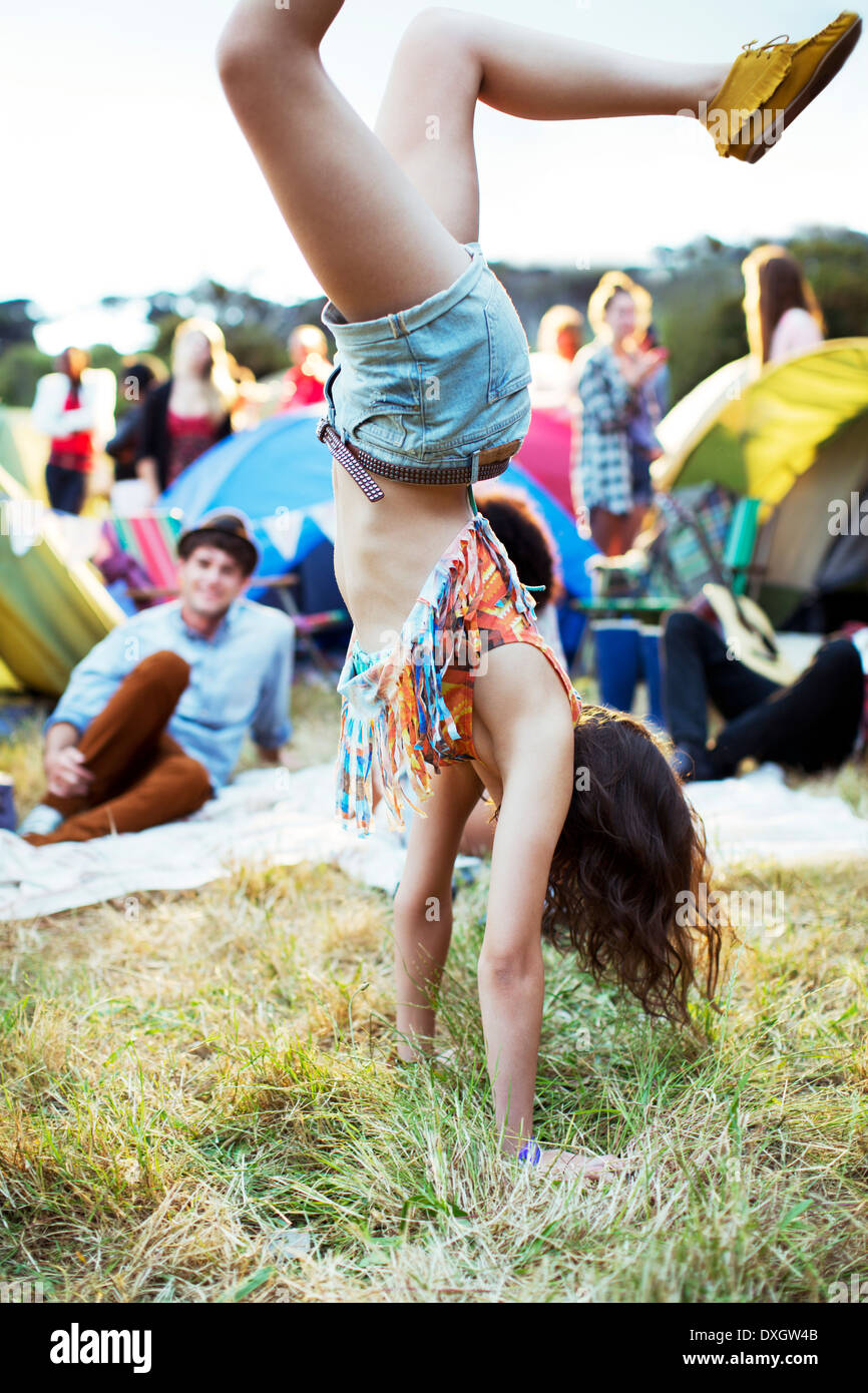 Woman doing handstand outside tents at music festival Stock Photo
