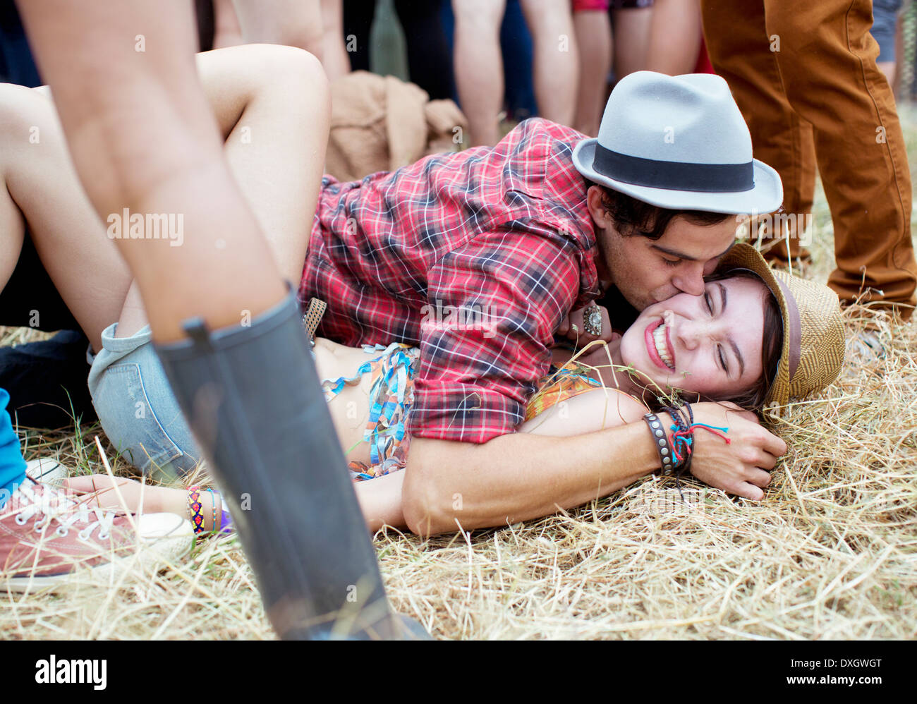 Couple kissing in grass at music festival Stock Photo