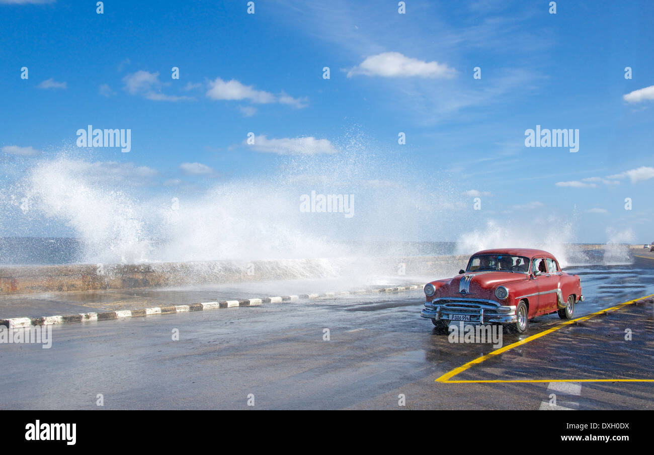 Vintage American car with waves splashing over Malecon Vedado Havana Cuba Stock Photo