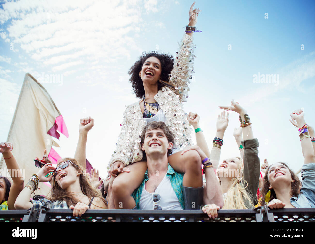 Cheering woman on manÍs shoulders at music festival Stock Photo