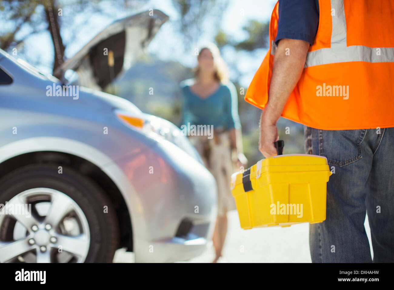Roadside mechanic with toolbox arriving to help woman Stock Photo