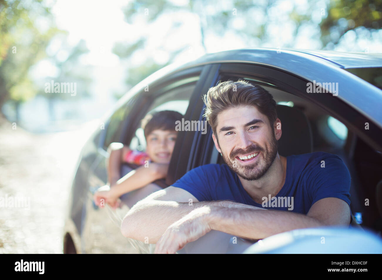 Portrait of smiling father and son leaning out car windows Stock Photo