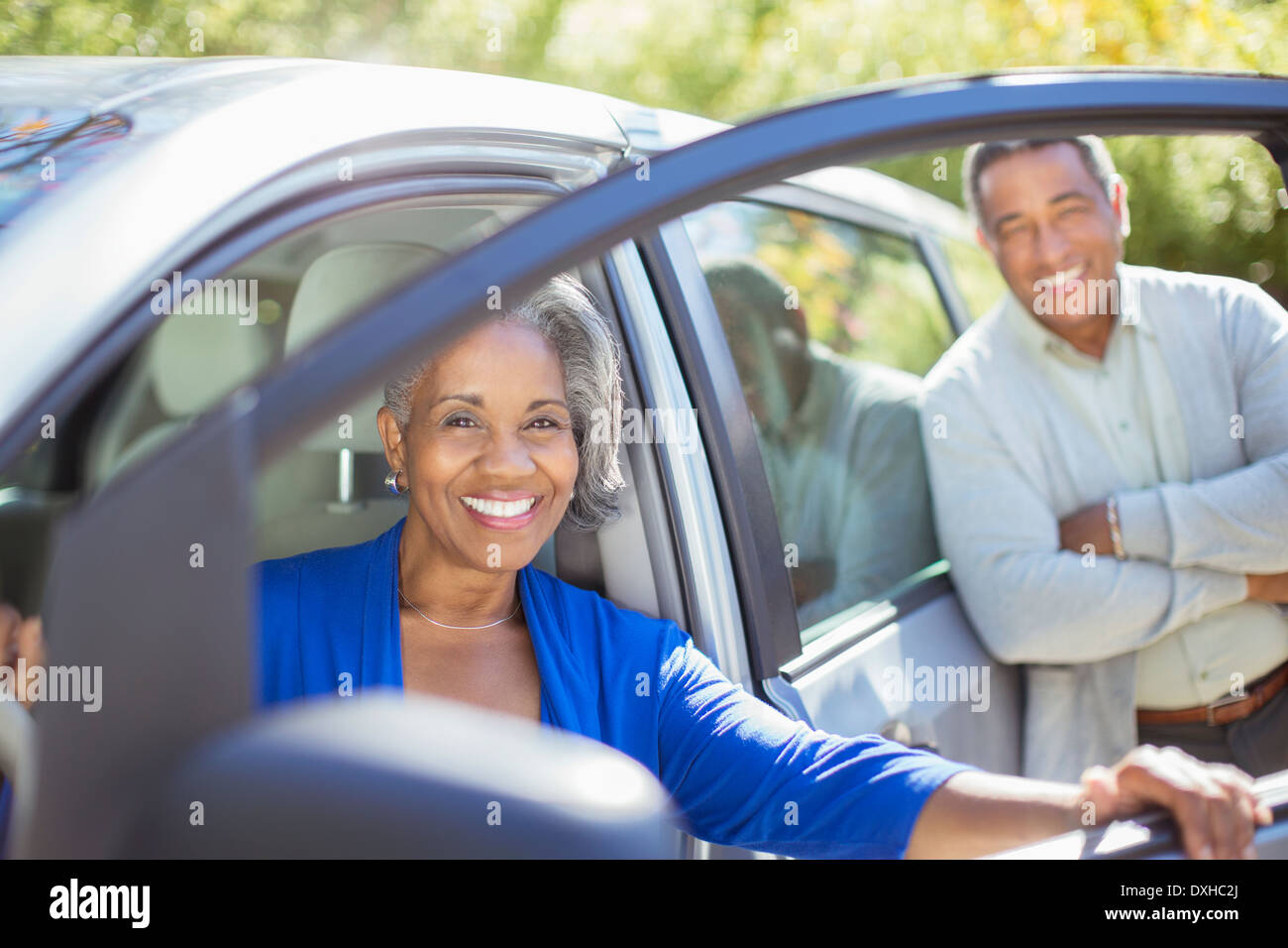 Portrait of happy senior couple inside and outside of car Stock Photo