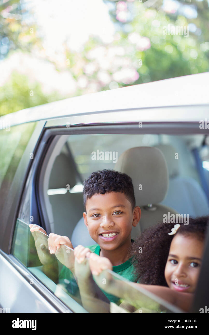Portrait of happy brother and sister leaning out car window Stock Photo