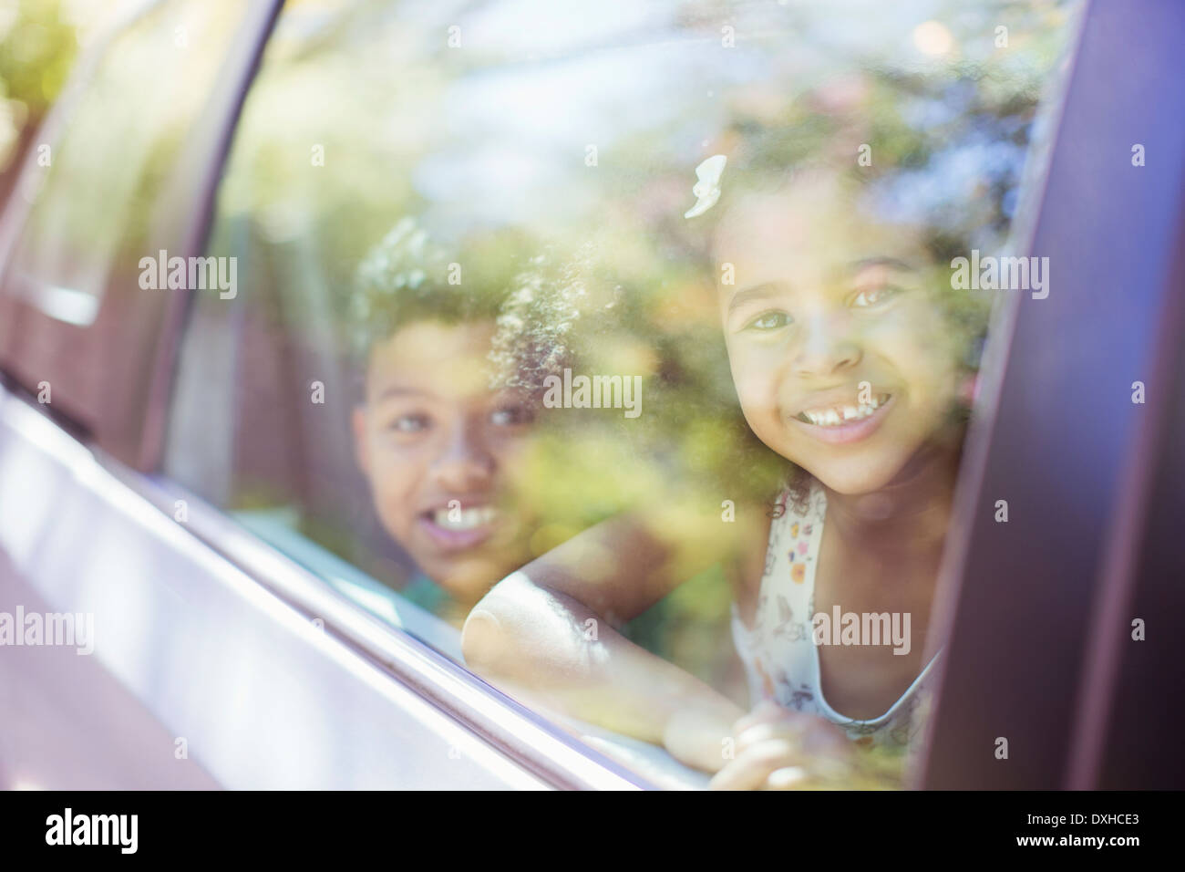 Portrait of happy brother and sister looking out car window Stock Photo