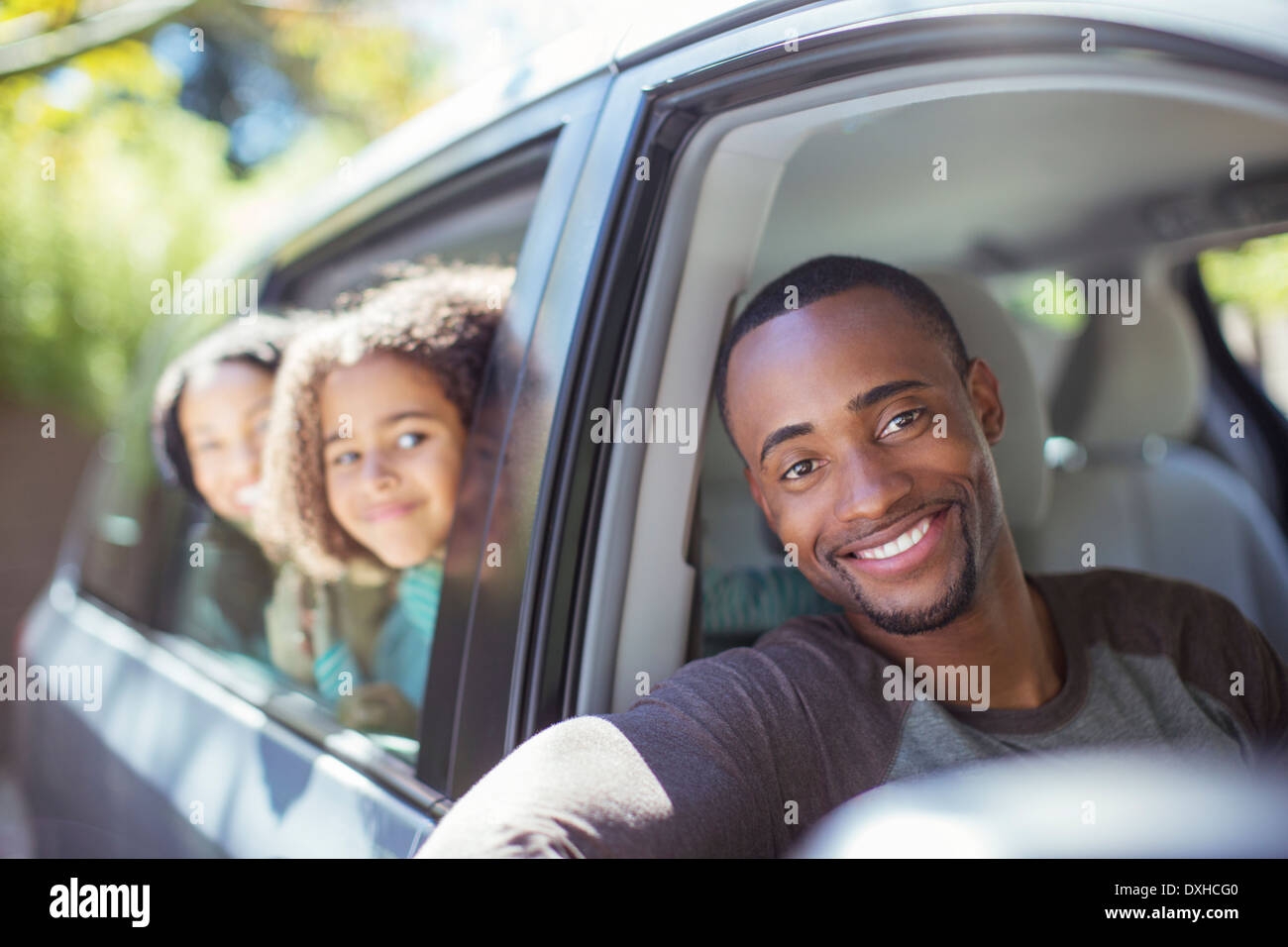 Portrait of happy family leaning out car windows Stock Photo