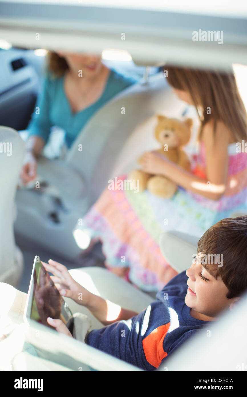 Boy using digital tablet in back seat of car Stock Photo