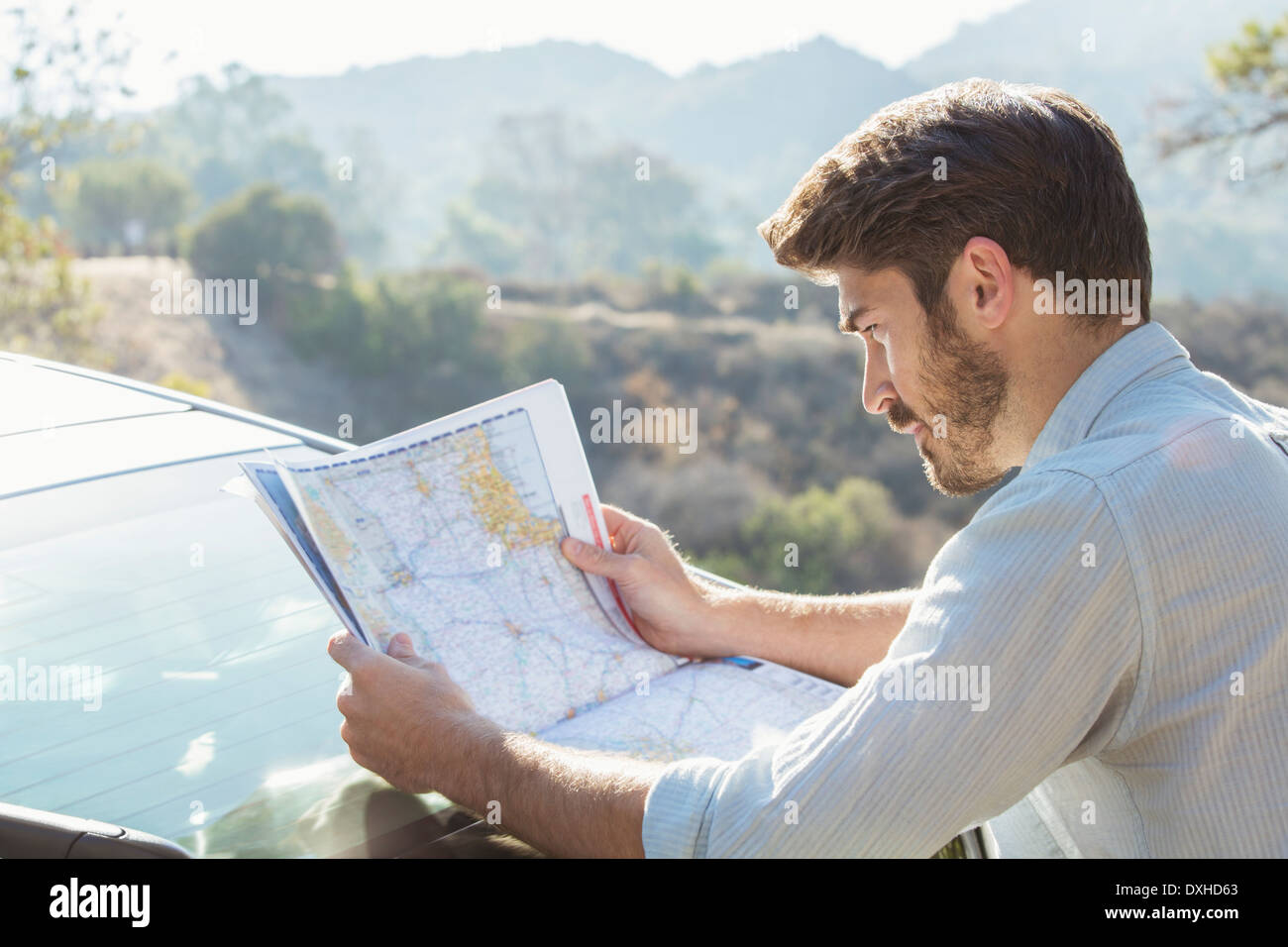 Man looking at map outside car Stock Photo