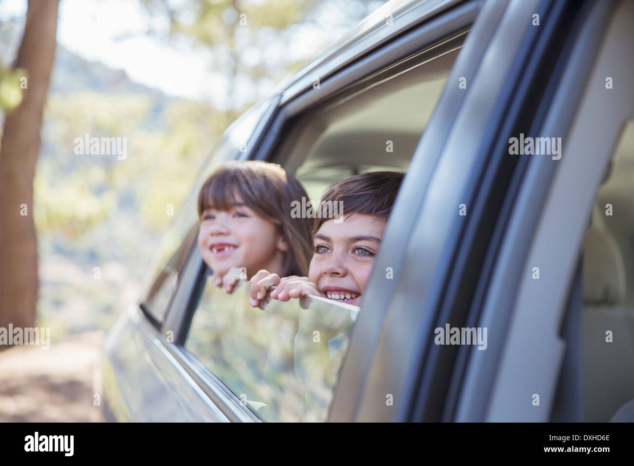 Happy brother and sister looking out car window Stock Photo