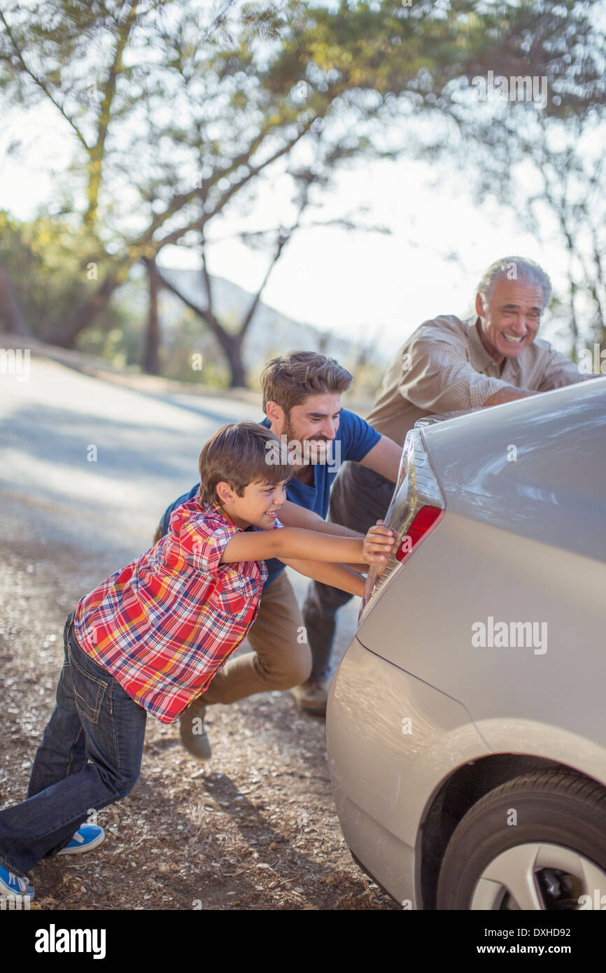 Multi-generation men pushing car at roadside Stock Photo