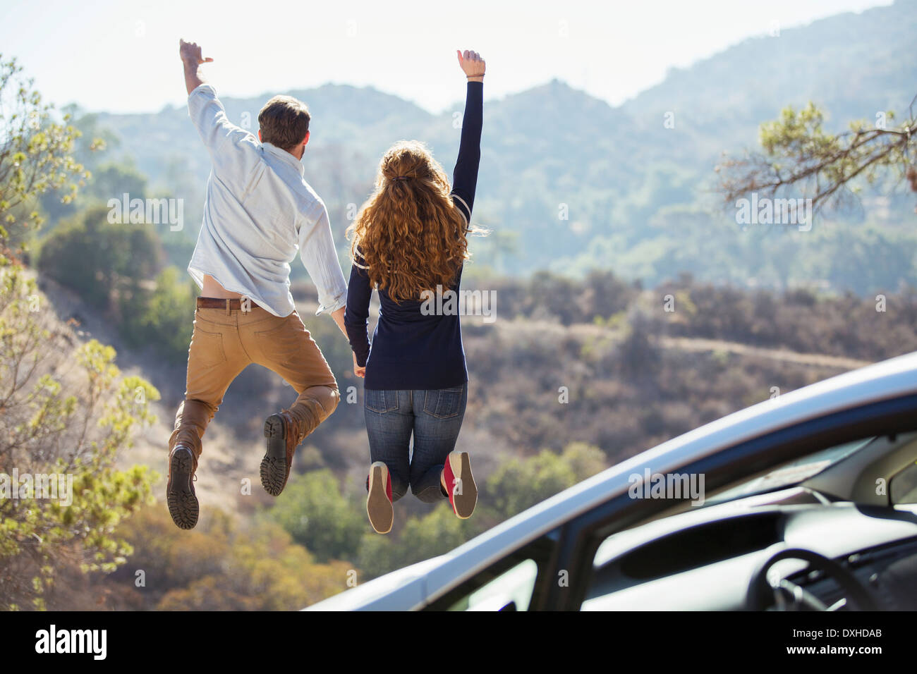 Enthusiastic couple jumping for joy outside car Stock Photo