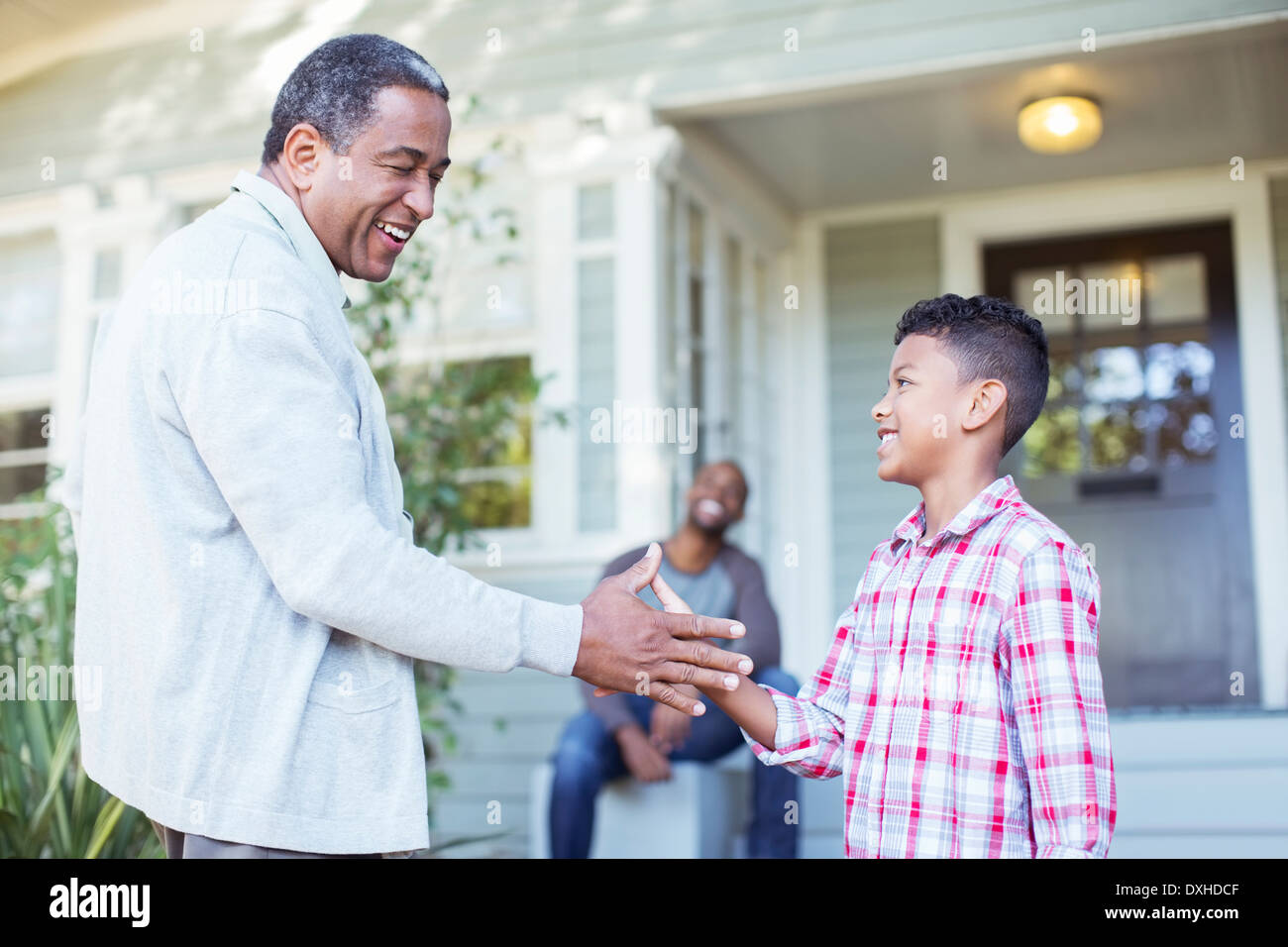 Grandfather and grandson exchanging special handshake outdoors Stock Photo