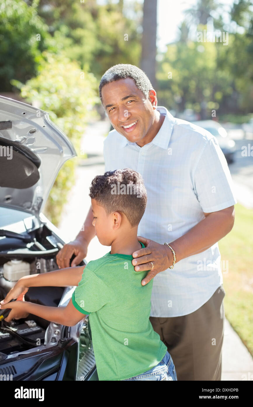 Portrait of smiling grandfather working on car engine with grandson Stock Photo