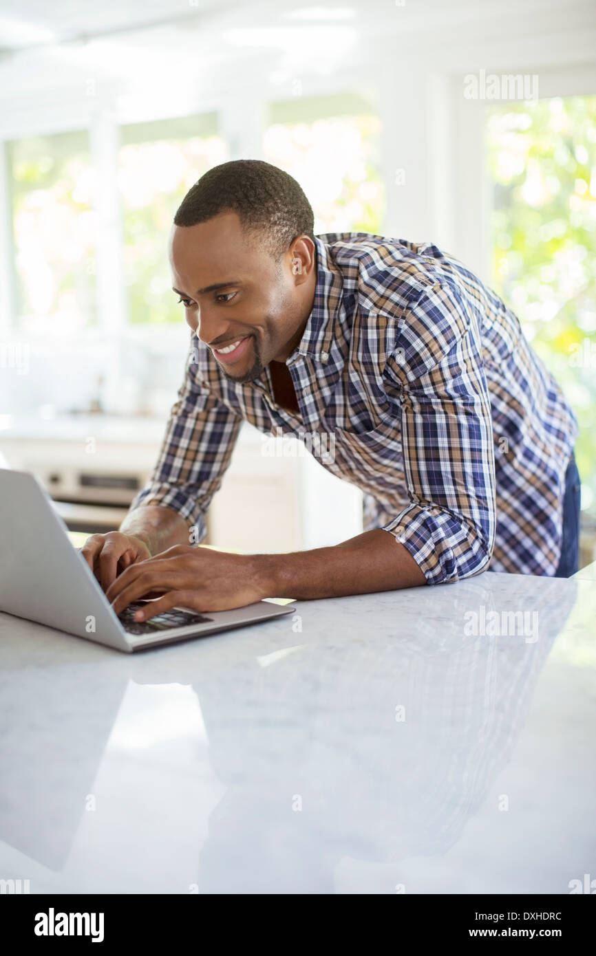 Man using laptop in kitchen Stock Photo