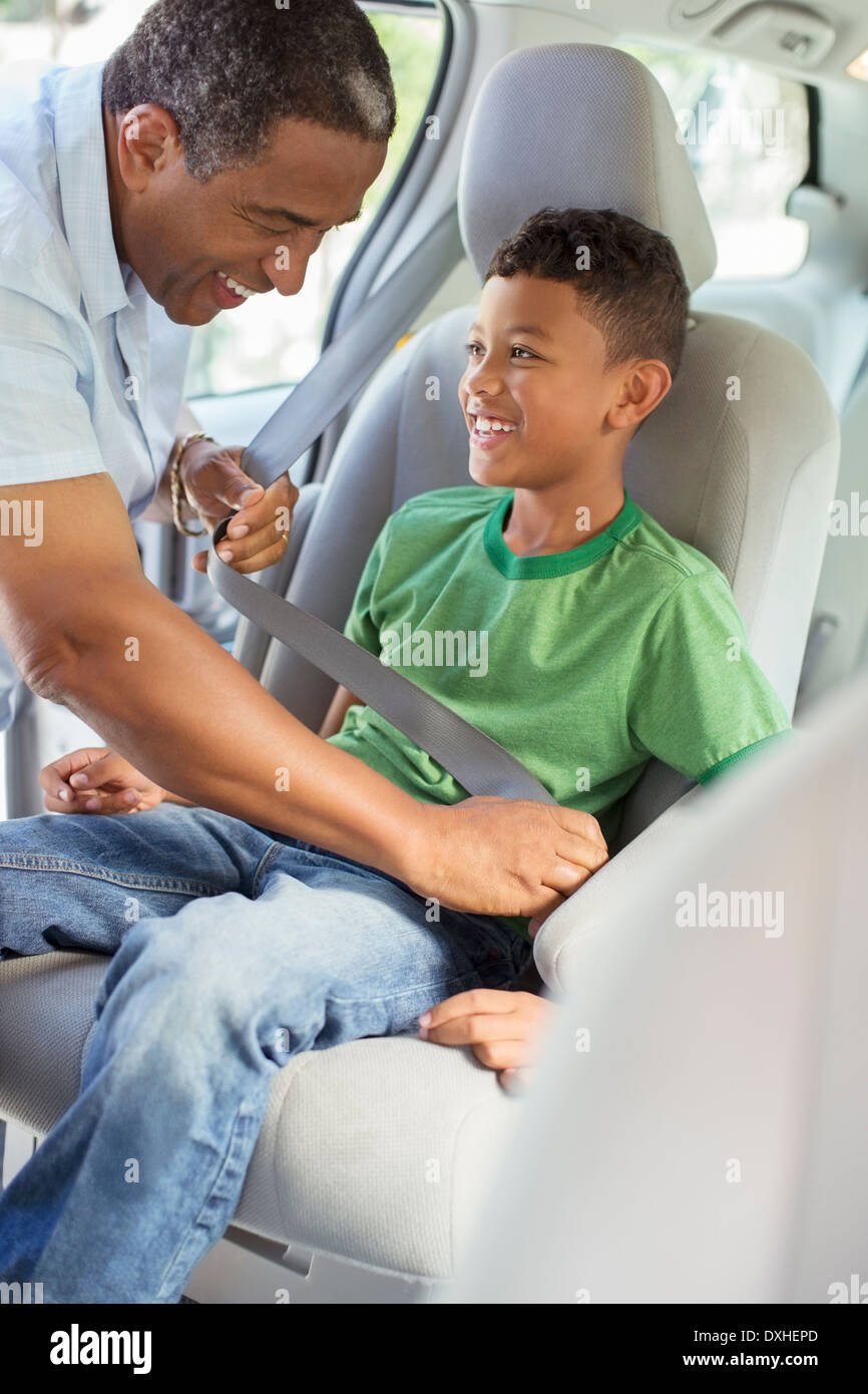 Grandfather fastening grandsonÍs seat belt in back seat of car Stock Photo
