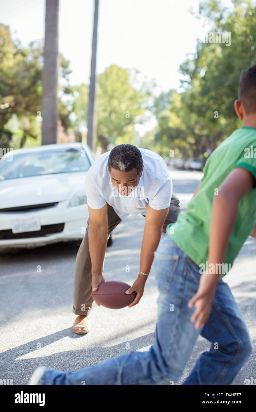 Grandfather and grandson playing football in street Stock Photo