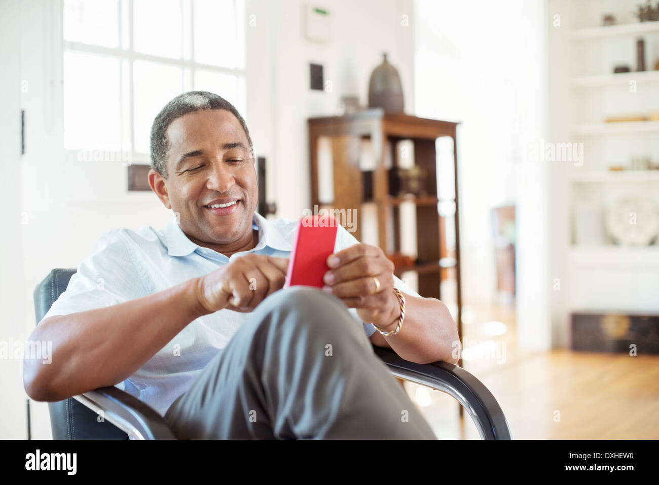 Senior man text messaging with cell phone in living room Stock Photo